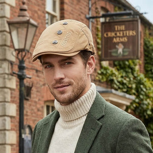 Male model wearing a khaki cotton flat cap with a cream turtleneck and green blazer in a British old-money outfit.